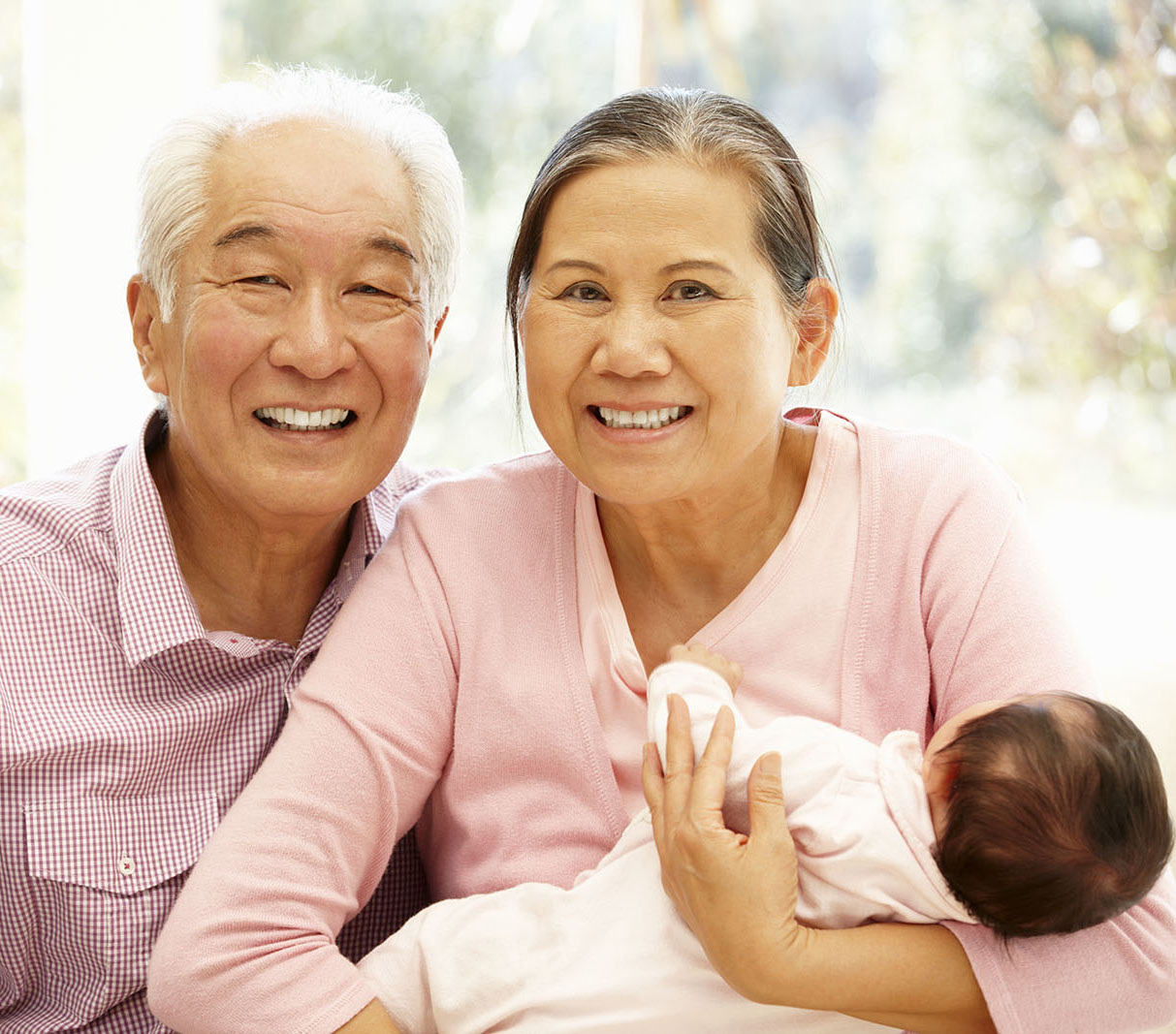 Happy grandparents hold their infant grandchild