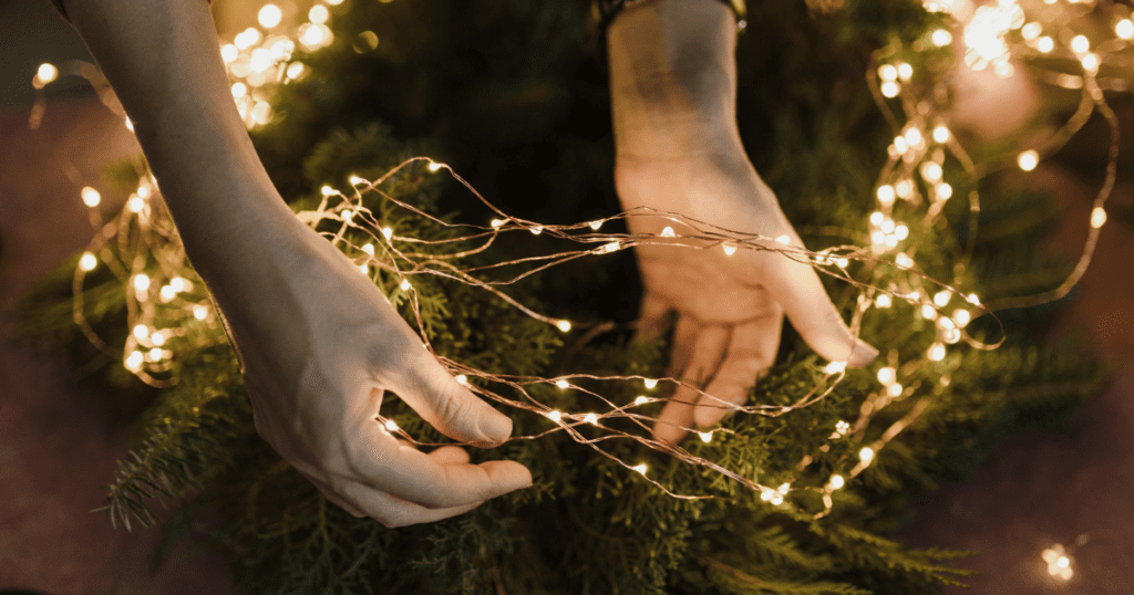 Person stringing holiday lights on wreath