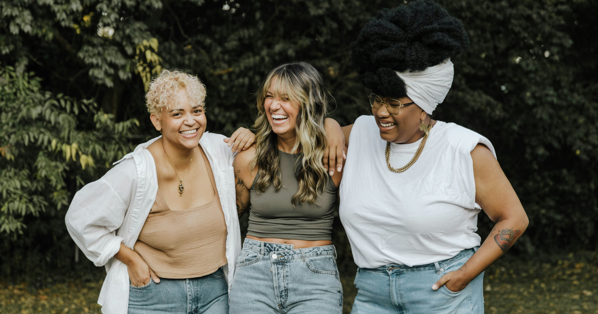 Three woman with their arms around each other smiling