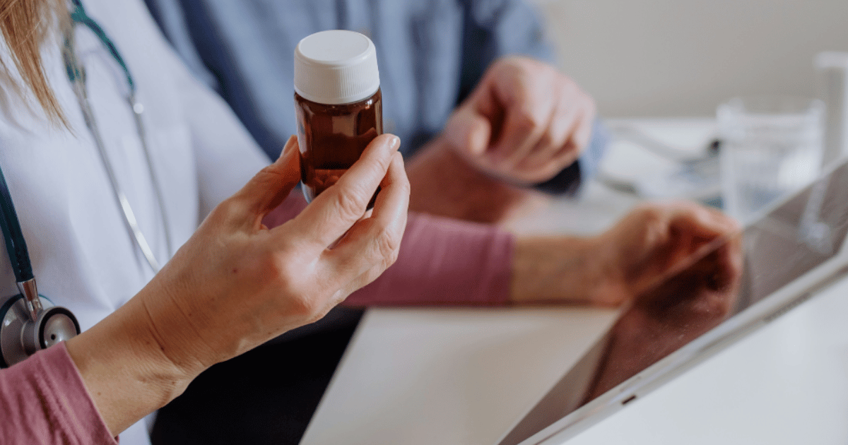 A doctor holding an antibiotic prescription while speaking with a patient